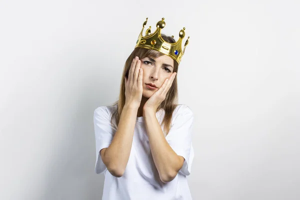 Mujer joven con una corona en la cabeza y una cara triste sobre un fondo claro. Concepto de reina, suerte, enfermedad, aburrimiento, problemas, sueño, meta, aspiración. Banner — Foto de Stock
