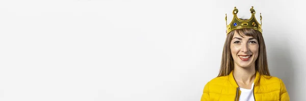 노란 자켓을 입고 밝은 배경에 금관을 쓰고 있는 젊은 여성. 웃음, 놀래키기, 키스. 여왕, 행운, 최고, 승리, 승리의 개념. 배너 — 스톡 사진