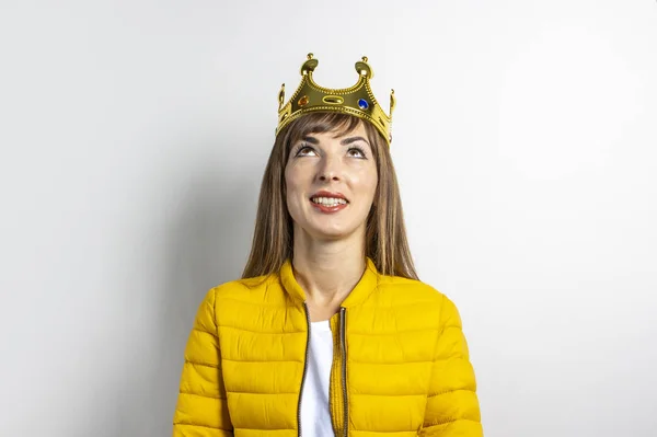 노란 자켓을 입고 밝은 배경에 금관을 쓰고 있는 젊은 여성. 웃음, 놀래키기, 키스. 여왕, 행운, 최고, 승리, 승리의 개념. 배너 — 스톡 사진