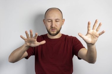 Gözleri kapalı ve kollarını hafif bir arka planda açmış genç bir adam. Gözleri kapalı bir şey arama kavramı, zayıf görme, körlük, bir şey için gözlerini kapama