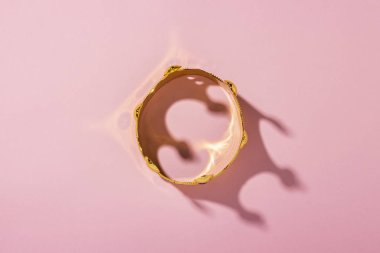 Pembe arka planda altın taç. Düz yatış, üst görünüm