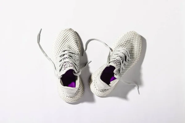 Zapatillas blancas bajo la luz del sol sobre un fondo blanco. Concepto de correr por la mañana, entrenamiento duro, correr, trotar, fitness. Banner. Piso tendido, vista superior . —  Fotos de Stock