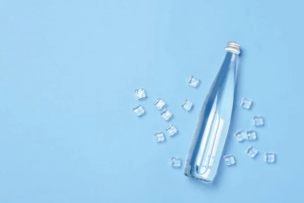 Glass bottle with clear water on a blue background with Ice cubes. Concept of health and beauty, water balance, thirst, heat, summer. Flat lay, top view. Banner — Stock Photo, Image