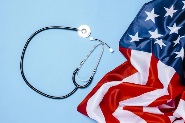 Doktorun steteskobu ve mavi arka planda Amerikan bayrağı. Usa tıp konsepti, yüksek seviye, sağlık sigortası, en iyi ilaç, aşı, virüs, salgın hastalık. Düz yatış, üst görünüm — Stok fotoğraf