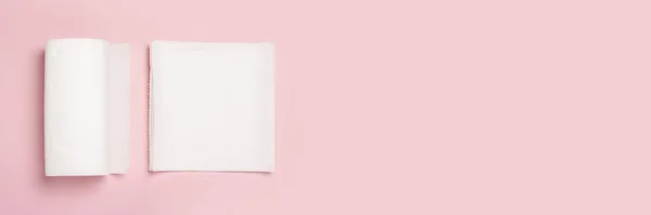 Rol van papieren handdoeken en enkele stukken handdoeken op een roze achtergrond. Concept is 100 natuurlijk product, delicaat en zacht. Vlakke lay, bovenaanzicht. Banner — Stockfoto