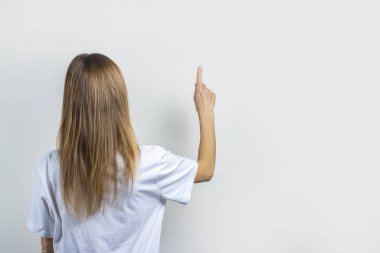 Genç bir kadın arka plandaki bir şeye dokunuyor ya da itiyor.