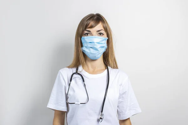 Tıbbi maskeli genç bir kadın ve arka planda steteskop. Pankart. Konsept doktor, yüksek seviye tıp, aşı, doktora git. — Stok fotoğraf