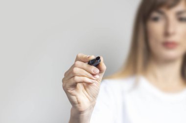 Genç bir kadın elinde mavi bir kalem tutuyor ve arka planına bir şeyler yazıyor. Pankart