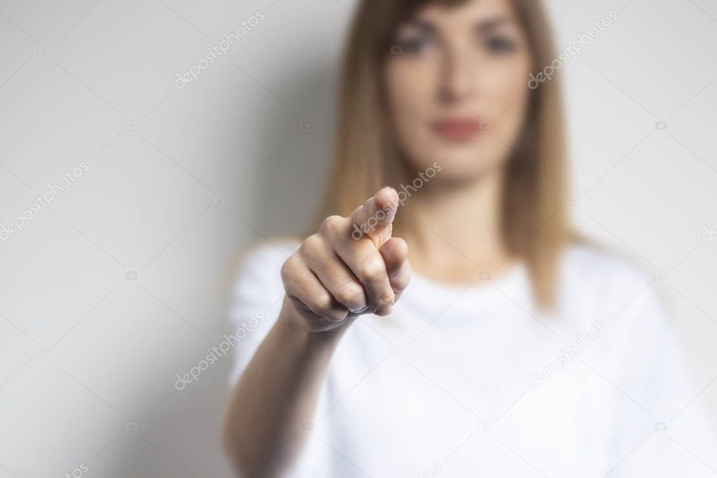 Young woman points a finger at something on a light background