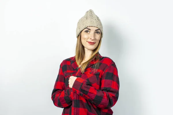 Mulher jovem com um sorriso em um chapéu, uma camisa vermelha e uma camiseta branca em um fundo branco. Conceito elegante, inverno, estilo adolescente, choque, surpresa. Banner — Fotografia de Stock