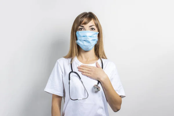 Jonge vrouw met een medisch masker en een stethoscoop op een lichte achtergrond. Een spandoek. Concept arts, hoog niveau medische geneeskunde, vaccinatie, bezoek aan de arts — Stockfoto