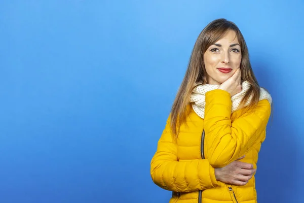 Young woman in a yellow jacket posing on a blue background. Concept winter and autumn, clothing for the season. Banner
