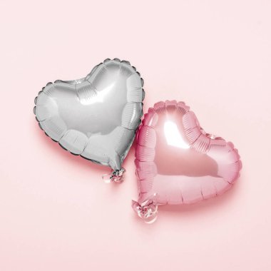 Pembe arka planda kalp şeklinde iki pembe hava balonu. Sevgililer Günü konsepti, düğün dekorasyonu. Folyo topları. Düz yatış, üst görünüm
