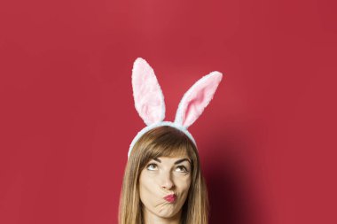 Pembe arka planda tavşan kulaklı güzel bir kadın. Paskalya konsepti