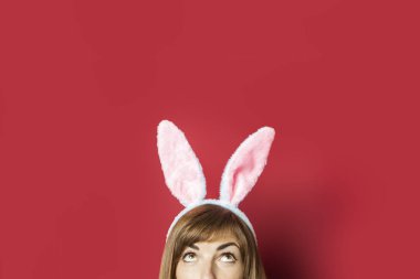 Pembe arka planda tavşan kulaklı güzel bir kadın. Paskalya konsepti