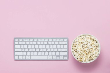 Klavye ve pembe bir arka plan üzerinde patlamış mısır kase. Film izlerken kavramı, Tv gösterir ve çevrimiçi gösterir. Düz yatıyordu, en iyi görünümü.