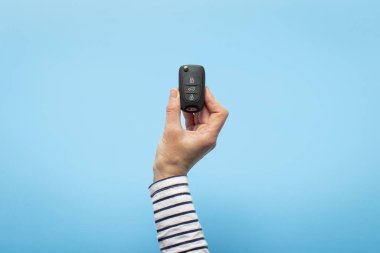 Kadın eli mavi arka planda arabanın anahtarlarını tutuyor. Konsept araba, araba kiralama, hediye, sürüş dersleri, ehliyet. Pankart. Düz yatış, üst görünüm