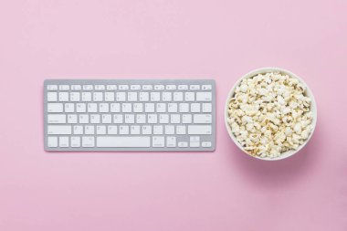 Klavye ve pembe bir arka plan üzerinde patlamış mısır kase. Film izlerken kavramı, Tv gösterir ve çevrimiçi gösterir. Düz yatıyordu, en iyi görünümü.