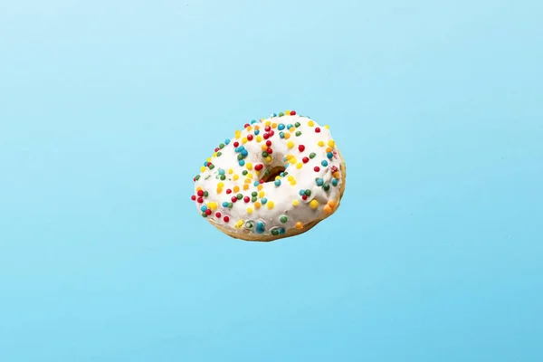 Voando em donut de ar com cobertura branca em um fundo azul. Padaria, conceito de cozedura. Levitação — Fotografia de Stock