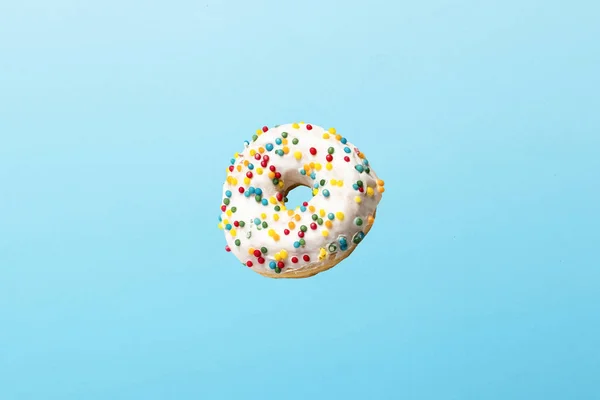 Voando em donut de ar com cobertura branca em um fundo azul. Padaria, conceito de cozedura. Levitação — Fotografia de Stock