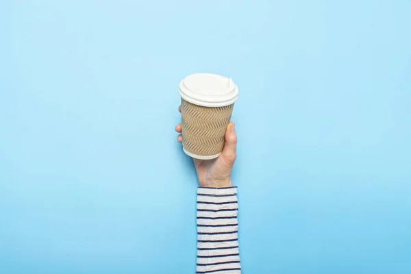 La mano femenina sostiene una taza de papel con café sobre un fondo azul. Concepto de café, una bebida caliente, desayuno. Banner Plano laico, vista superior — Foto de Stock