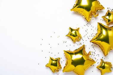 Hava altın balonları yıldız şeklinde ve beyaz arka planda şekerler. Tatil, parti, fotoğraf bölgesi, dekorasyon. Banner Düz yatar, üst görünüm