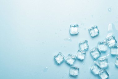 Mavi zemin üzerinde su olan buz küpleri. İçkiler için buz konsepti. Pankart. Düz yatış, üst görünüm