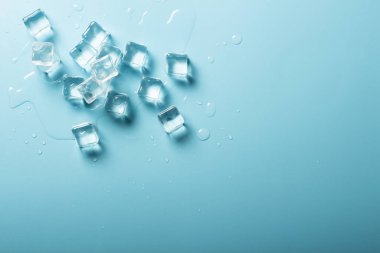 Mavi zemin üzerinde su olan buz küpleri. İçkiler için buz konsepti. Pankart. Düz yatış, üst görünüm
