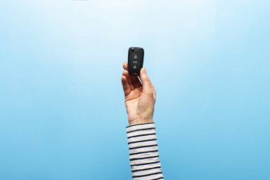 Kadın eli mavi arka planda arabanın anahtarlarını tutuyor. Konsept araba, araba kiralama, hediye, sürüş dersleri, ehliyet. Pankart. Düz yatış, üst görünüm