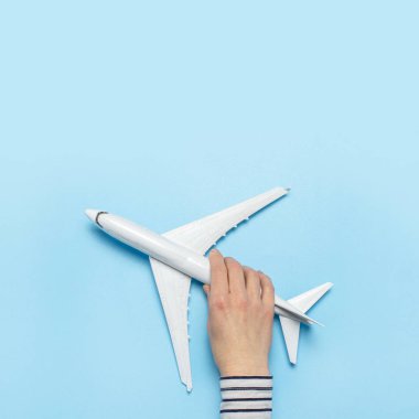 Kadın eli mavi arka planda bir uçağı tutuyor. Konsept uçuş, biletler, rezervasyon, uçuş araması, seyahat. Pankart. Düz yatış, üst görünüm
