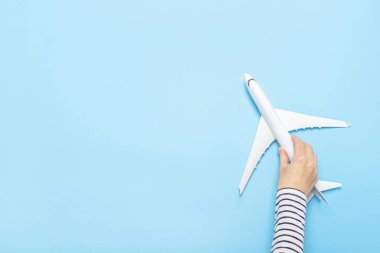 Kadın eli mavi arka planda bir uçağı tutuyor. Konsept uçuş, biletler, rezervasyon, uçuş araması, seyahat. Pankart. Düz yatış, üst görünüm