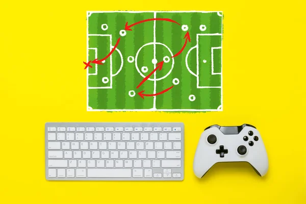 黄色背景上的键盘和控制器。增加了一个足球场计划和战术。游戏控制台的概念。平躺在地上，俯瞰四周. — 图库照片