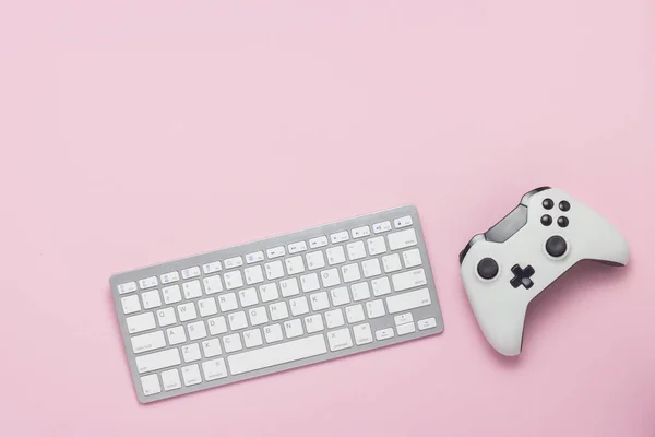 Tangentbord och gamepad på rosa bakgrund. Begreppet spelet på konsolen, underhållning, fritid, onlinespel. Platt ligg, ovanifrån. — Stockfoto