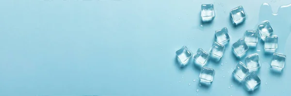 Eiswürfel mit Wasser auf blauem Hintergrund. Eiskonzept für Getränke. Banner. flache Lage, Draufsicht — Stockfoto