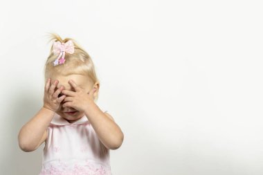 Küçük çocuk ellerini hafif bir arka planda tutarak yüzünü kapatıyor. Korku, korku, aile içi şiddet, kilitlenme oyunu