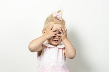 Küçük çocuk ellerini hafif bir arka planda tutarak yüzünü kapatıyor. Korku, korku, aile içi şiddet, kilitlenme oyunu