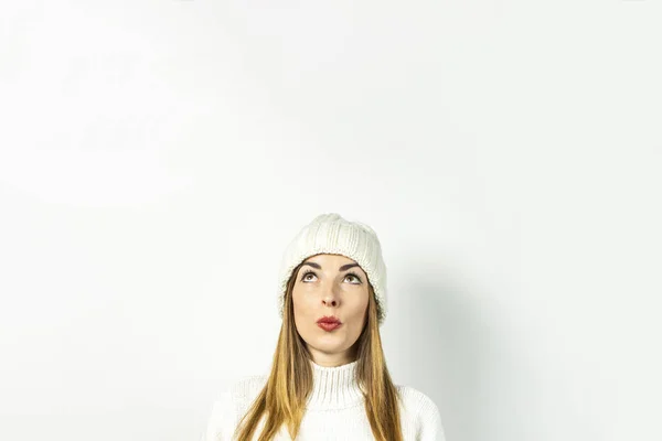 Mujer joven con una cara pensativa en un sombrero y suéter sobre un fondo blanco. Concepto invierno, otoño, elegante, Navidad, Año Nuevo, sorpresa, shock, planificación, sueño. Banner — Foto de Stock