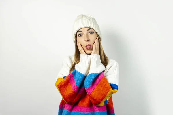 Mulher jovem mostra a língua em um chapéu e suéter em um fundo branco. Conceito inverno, outono, elegante, Natal, Ano Novo, surpresa, choque, planejamento, sonho. Banner — Fotografia de Stock