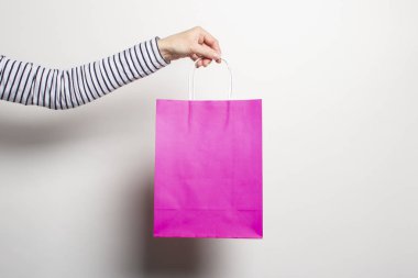 Kadın eli beyaz arka planda bir alışveriş çantası tutuyor. Konsept alışveriş, indirim, indirim. Pankart