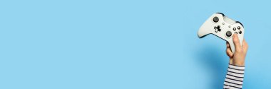 Kadın el, mavi arka planda bir av alanı tutuyor. Oyun konsepti, e-spor, eğlence, oyun endüstrisi, video oyunları. Pankart. Düz yatış, üst görünüm