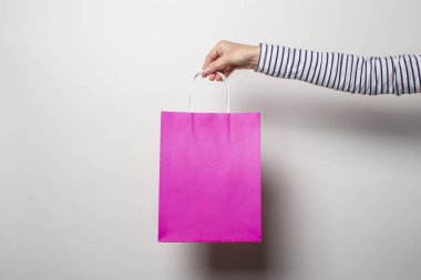 Kadın eli beyaz arka planda bir alışveriş çantası tutuyor. Konsept alışveriş, indirim, indirim. Pankart