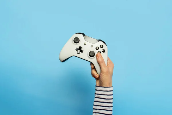 Kvinnlig hand hålla en gamepad på en blå bakgrund. Begreppet spel, e-sport, fritid, spelindustrin, videospel. Banner. Platt ligg, ovanifrån — Stockfoto