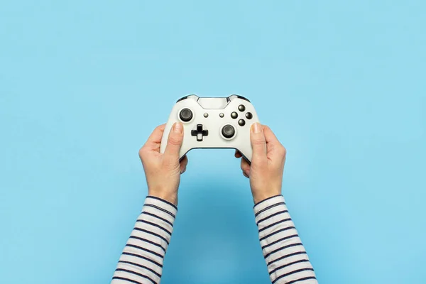 Kvinnliga händer håller en gamepad på en blå bakgrund. Begreppet spel, e-sport, fritid, spelindustrin, videospel. Banner. Platt ligg, ovanifrån — Stockfoto
