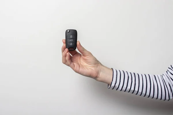 female hand holds a car key on a white background