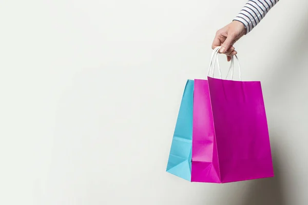 Mão feminina segura sacos de compras em um fundo branco. Conceito compras, desconto, venda. Banner — Fotografia de Stock