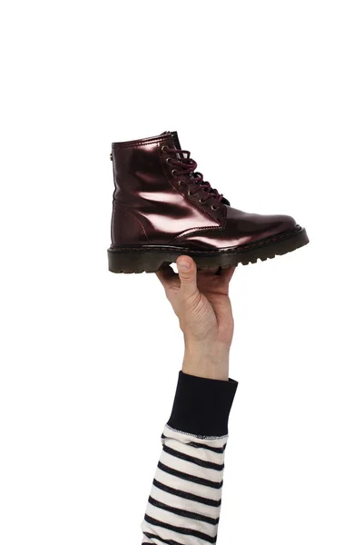 Χέρι κρατήστε μια μπότα σε ένα απομονωμένο φόντο. Έννοια της επιλογής των υποδημάτων, ψώνια, επισκευή παπουτσιών — Φωτογραφία Αρχείου