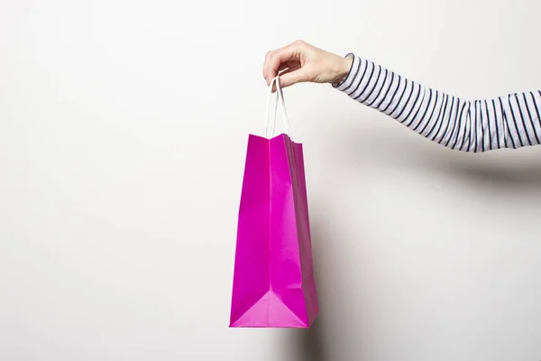 Γυναικείο χέρι κρατά μια τσάντα για ψώνια σε λευκό φόντο. Αγορές Concept, εκπτώσεις, εκπτώσεις. Μπάνερ — Φωτογραφία Αρχείου