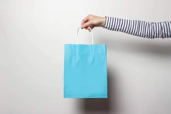 Mão feminina segura um saco de compras em um fundo branco. Conceito compras, desconto, venda. Banner — Fotografia de Stock