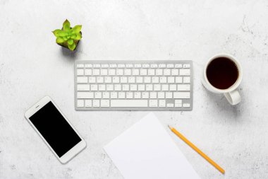 Klavye, boş bir kağıt ve bir kalem, bir telefon, bir fincan kahve ve çimento kaplı bir bitki. Konsept ofis, serbest çalışma, evde çalışma. Pankart. Üst manzara, düz uzanma.