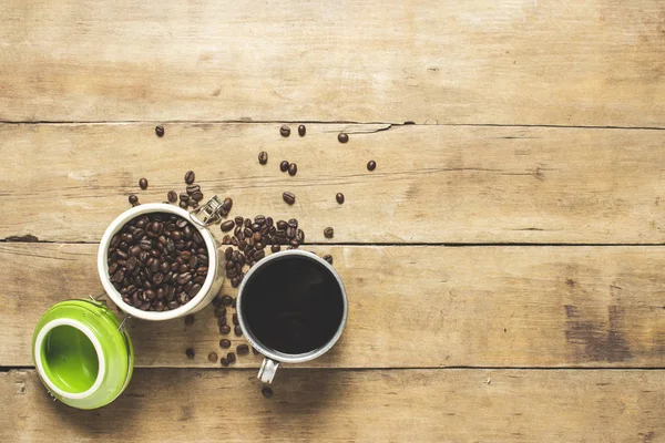 cup with fresh coffee and a can with coffee grains, coffee beans are scattered on a wooden table. Banner. Coffee concept, plantation, processing, collection. Top view, flat lay.